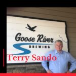 Photo of podcast guest Terry Sando in front of Goose River Brewing sign