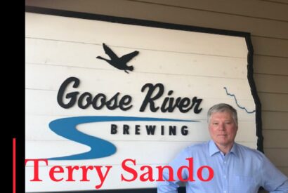 Photo of podcast guest Terry Sando in front of Goose River Brewing sign